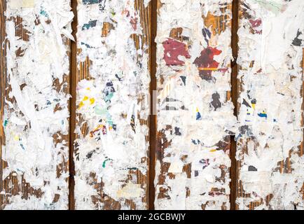 Des affiches déchirées colorées sur les vieux murs de grunge comme arrière-plan ou texture Banque D'Images
