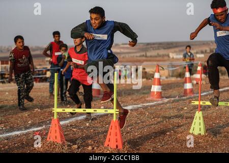 Idlib City, Syrie. 07e août 2021. Les enfants syriens participent à un match d'athlétisme dans le cadre d'un petit événement olympique organisé pour les enfants déplacés par l'Organisation de secours et de développement Violet. L'événement sportif est organisé en conjonction avec les Jeux Olympiques de Tokyo en 2020 pour sensibiliser les populations des camps de réfugiés contraintes à leur déplacement interne en raison du conflit civil en Syrie. Credit: Aras Alkharboutli/dpa/Alamy Live News Banque D'Images