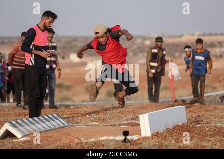 Idlib City, Syrie. 07e août 2021. Un enfant syrien participe à un match d'athlétisme dans le cadre d'un petit Jeux Olympiques organisé pour les enfants déplacés par l'Organisation Violet pour le secours et le développement. L'événement sportif est organisé en conjonction avec les Jeux Olympiques de Tokyo en 2020 pour sensibiliser les populations des camps de réfugiés contraintes à leur déplacement interne en raison du conflit civil en Syrie. Credit: Aras Alkharboutli/dpa/Alamy Live News Banque D'Images