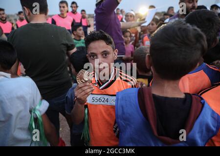 Idlib City, Syrie. 07e août 2021. Un enfant syrien bénéficie d'une médaille symbolique lors d'un petit Olympiade organisé pour les enfants déplacés par l'Organisation Violet pour le secours et le développement. L'événement sportif est organisé conjointement avec les Jeux Olympiques de Tokyo en 2020 pour attirer l'attention sur les conditions dans les camps de réfugiés de ceux qui ont été contraints à des déplacements internes en raison du conflit civil en Syrie. Credit: Aras Alkharboutli/dpa/Alamy Live News Banque D'Images