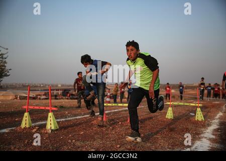 Idlib City, Syrie. 07e août 2021. Les enfants syriens participent à un match d'athlétisme dans le cadre d'un petit Jeux Olympiques organisé pour les enfants déplacés par l'Organisation Violet pour le secours et le développement. L'événement sportif est organisé en conjonction avec les Jeux Olympiques de Tokyo en 2020 pour sensibiliser les populations des camps de réfugiés contraintes à leur déplacement interne en raison du conflit civil en Syrie. Credit: Aras Alkharboutli/dpa/Alamy Live News Banque D'Images