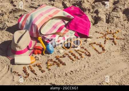 Inscription vitamine D avec forme de soleil, accessoires pour la détente et les enfants jouant sur le sable à la plage. Prévention de la carence en vitamine D. Banque D'Images