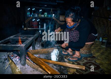 une femme tribale d'apatani qui fait du thé chez elle près d'un lieu de feu en soirée est prise au ziro arunachal pradesh inde. c'est l'une des plus anciennes tribus de Banque D'Images