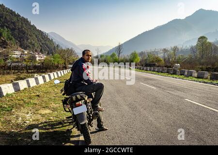 homme assis à moto sur la route du tarmac avec une belle vue naturelle le matin image est prise au shergaon arunachal pradesh inde. Banque D'Images