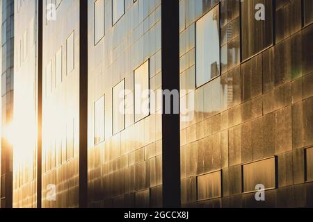 Le soleil couchant se reflète dans les fenêtres d'un grand immeuble de bureaux en verre dans le vieux centre de Bucarest. Banque D'Images