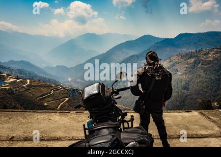 une jeune motard avec sa moto chargée et une vue naturelle immaculée le matin est prise à la bomdila arunachal pradesh inde. Banque D'Images