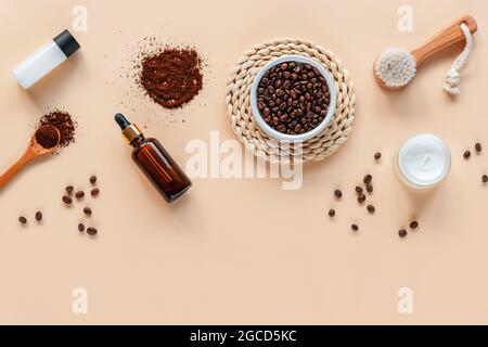 Accessoires de bain et cosmétiques naturels, ingrédients pour le gommage du café, brosse pour le visage, bouteille de sérum sur fond beige avec espace de copie. Vue de dessus, plan d'appartement Banque D'Images