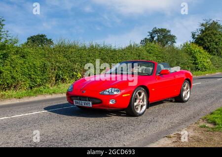 2002 rouge Jaguar XK8 sports cabrio, 2 portes 4196 cc essence en route vers Capesthorne Hall Classic July car show, Cheshire, Royaume-Uni Banque D'Images