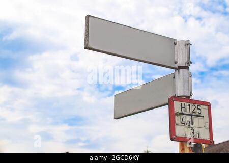 Panneaux de signalisation directionnels vierges blanc contre ciel bleu. Banque D'Images