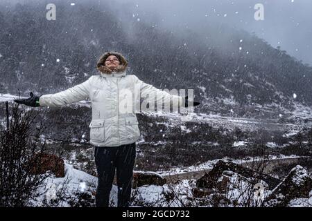 jeune fille qui profite de la chute de neige dans les montagnes de l'himalaya le matin, l'image est prise au lac madhuri tawang arunachal pradesh. Banque D'Images