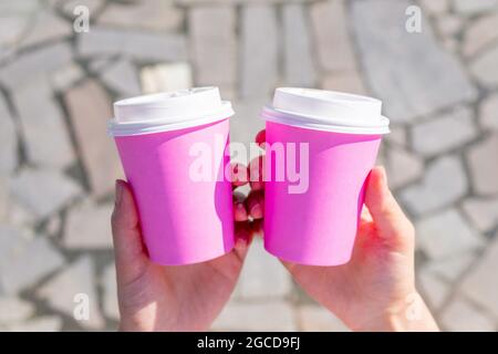 La personne tient deux tasses jetables roses pour le café ou le thé Banque D'Images