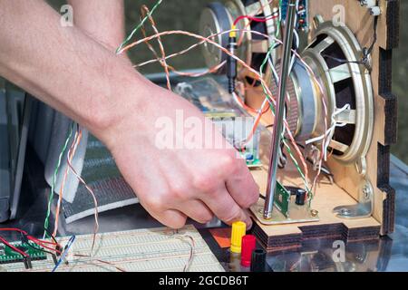 Les mains connectent les fils et les contacts électroniques de la radio maison. Passe-temps à faire des choses rétro. Banque D'Images