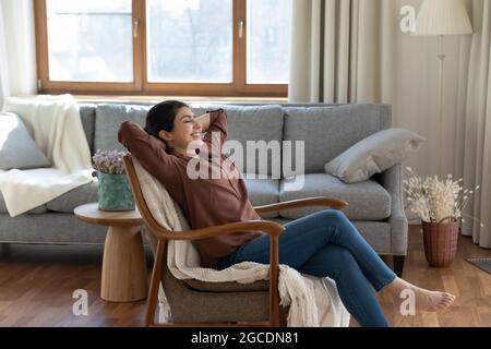 Une femme indienne calme se repose sur une chaise rêvant de jour Banque D'Images