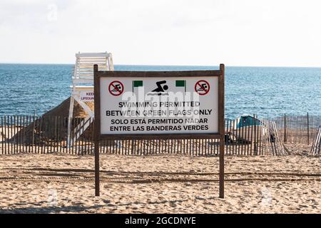 La natation est autorisée entre les drapeaux verts uniquement sur une plage avec un stand de gardien de vie et le long Islnad Sound en arrière-plan. Banque D'Images