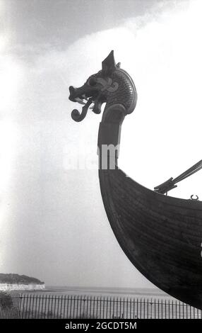 Années 1960, historique, la tête du bateau viking ou du bateau à longue 'Hugin' exposé sur la côte sur le sommet de la falaise de Pegwell Bay, Ramsgate, Kent, Angleterre, Royaume-Uni. Un voilier reconstruit, le Hugin, un cadeau du gouvernement danois pour commémorer le 1500 anniversaire de Hengist et Horsa, leaders de l'invasion anglo-saxonne à Ebbsfleet, tout proche, est arrivé à Viking Bay, Broadlairs en 1949. C'est une réplique du navire Gokstad, vers 890. Banque D'Images