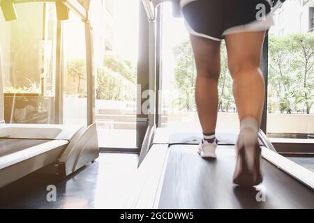 Gros plan chaussures femme course sur tapis roulant. Femme aux jambes musculaires en salle de sport Banque D'Images