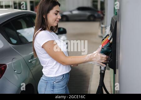 La femme se prépare à faire le plein à la station-service. Femme remplissant à la main le carburant essence de benzine dans la voiture. Concept des prix de l'essence Banque D'Images