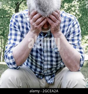 Vieux déprimé assis sur le banc dans un parc. Banque D'Images