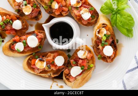 Vue de haut en bas d'un plateau de bruschetta avec une soucoupe de vinaigre balsamique au milieu. Banque D'Images