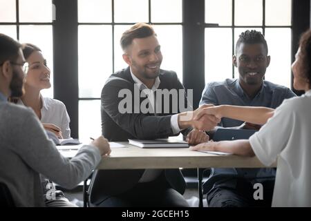 Des hommes d'affaires souriants se font une bonne connaissance lors d'une réunion Banque D'Images