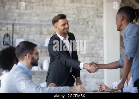 Souriant, divers hommes d'affaires se bousculer lors d'une réunion de bureau Banque D'Images
