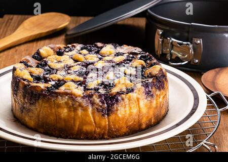 Vue latérale gros plan de délicieux bleuets maison fraîchement cuits et cheesecake crumble dans une plaque en céramique brune sur une grille de refroidissement en métal avec four en métal pi Banque D'Images