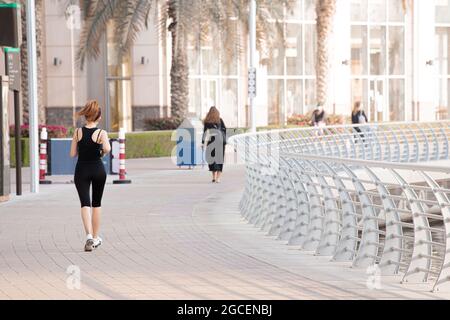 Une femme non identifiable fait un entraînement cardio et court le long du front de mer à Dubai Marina Banque D'Images