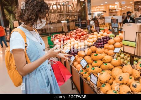 23 février 2021, Dubaï, Émirats arabes Unis : une femme portant un masque médical pendant la quarantaine du coronavirus a acheté de la nourriture et des fruits dans un supermarché et des chèques Banque D'Images