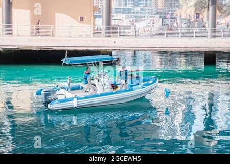 23 février 2021, Dubaï, Émirats arabes Unis : employés de services municipaux sur un bateau à moteur avec un filet de capture des ordures de la baie dans la Marina de Dubaï Banque D'Images