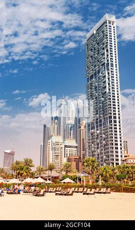 25 février 2021, Dubaï, Émirats Arabes Unis : il y a plein de transats et de parasols sur la plage dans la zone JBR, sur fond de spectaculaire puits de lumière résidentiels Banque D'Images