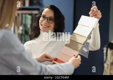 Un vendeur souriant présente des échantillons avec des tissus Banque D'Images