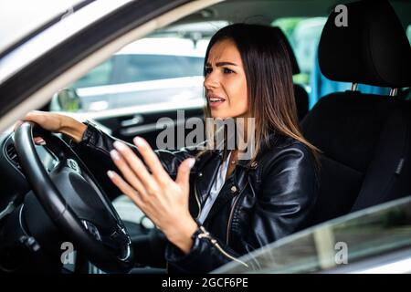 Femme mécontent de conduire la voiture et crier à quelqu'un Banque D'Images