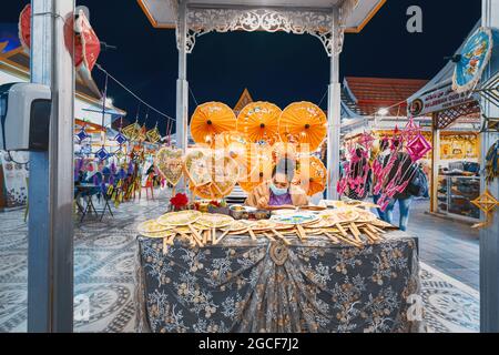 26 février 2021, Émirats Arabes Unis, Dubaï : une femme artisan peint des parasols lumineux à vendre aux touristes dans le pavillon de Thaïlande Banque D'Images