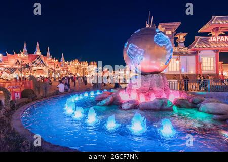 26 février 2021, Émirats Arabes Unis, Dubaï : fontaine illuminée et canal d'eau avec un globe de bronze sur la place dans Global Village Banque D'Images