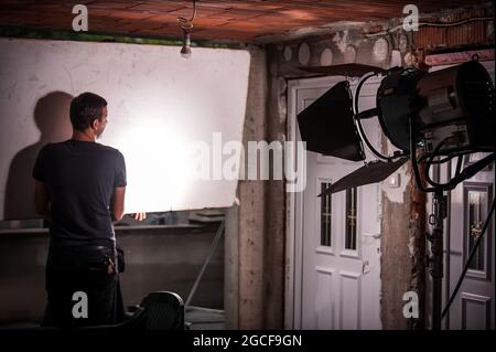 Derrière la scène. Technicien en éclairage de la réalisation du film ingénieur en électricité réglage du réflecteur et réglage des lumières intensité de diffusion pour la scène de film. Auge Banque D'Images