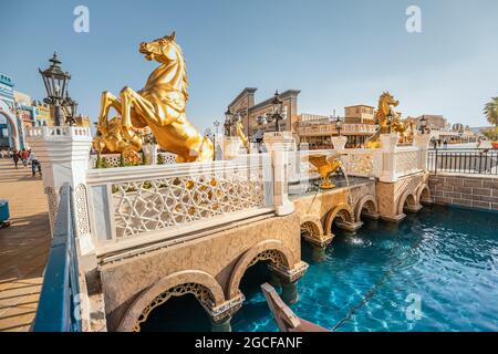 26 février 2021, Émirats Arabes Unis, Dubaï : pont avec chevaux d'or et chenal d'eau dans un village mondial Banque D'Images