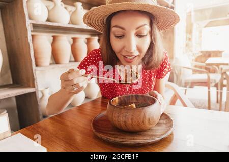 La bonne femme mange de la soupe kharcho de cuisine géorgienne ou du goulash à la viande hongroise dans un restaurant rustique. Banque D'Images