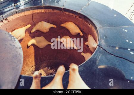 Cuisson de pains plats pour la fabrication de khachapuri dans un four traditionnel tandoor. Cuisine nationale géorgienne et caucasienne Banque D'Images