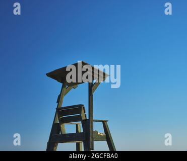 détail d'un fauteuil de sauvetage en bois sur une plage avec ciel bleu Banque D'Images