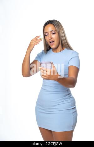 Un cliché isolé d'une femme hispanique blonde en robe bleue avec une expression surprise tout en lisant des informations sur le téléphone portable Banque D'Images