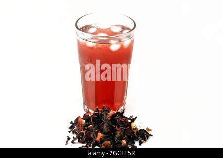 Verre de jus de Roselle frais et réfrigéré avec des herbes de Roselle séchées isolées sur fond blanc, un jus de wonjo de biscap avec des glaçons Banque D'Images