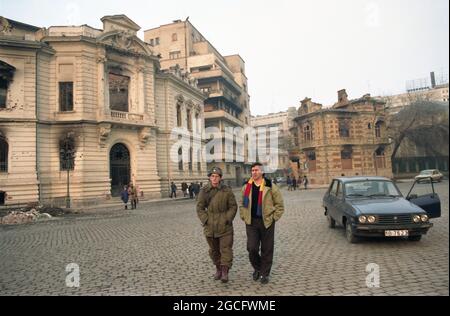 Bucarest, Roumanie, janvier 1990. L'acteur George Mihaita discutant avec les soldats dans la rue dans les jours sombres juste après la chute du communisme. Bâtiments historiques endommagés par des coups de feu. Banque D'Images