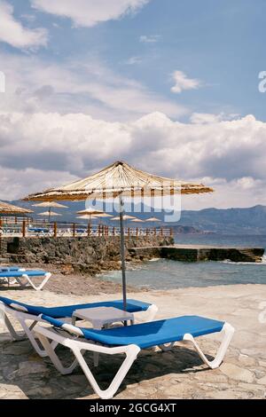 Chaises longues avec table sous un parasol Banque D'Images