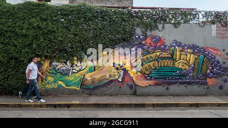 Deux hommes marchant devant l'art mural à San Jose, Costa Rica. Banque D'Images