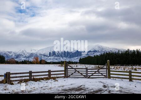 Le matin, après une chute de neige qui s'étend sur les terres agricoles rurales, les contreforts et les montagnes avec une clôture de ferme en bois, Springfield, Canterbury, Nouvelle-Zélande Banque D'Images