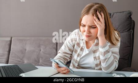 Jeune femme bouleversée sous le stress. Une femme confuse tenant la tête a reçu de mauvaises nouvelles au travail via un smartphone. Une jeune fille regarde l'écran du smartphone pendant Banque D'Images