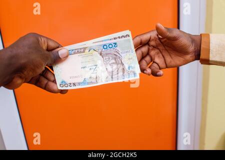Deux mains africaines recevant ou échangeant des billets de Naira nigérians, de l'argent ou de la monnaie Banque D'Images