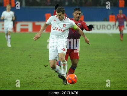 BUCAREST, ROUMANIE - 16 FÉVRIER 2012 : Peter Wisgerhof (L) de Twente et Leandro Tatu (R) de la FCSB photographié en action pendant la première étape du jeu de 32 de l'UEFA Europa League Round de 2011/12 entre la FCSB et le FC Twente à l'arène nationale. Banque D'Images