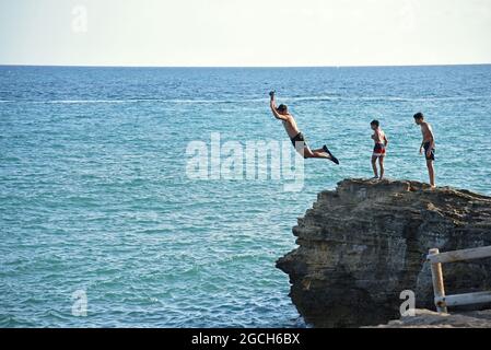 Roda de Bara, Espagne. 05 août 2021. Un jeune homme plonge dans la mer depuis une falaise à la plage du Roc de Sant Gaieta à Roda de Bara.les jeunes sautent des falaises à la plage du Roc de Sant Gaieta à Roda de Bara (Tarragone Espagne), une pratique qui est interdite, dangereux et peut causer de graves blessures corporelles et même la mort par l'impact contre les roches. Crédit : SOPA Images Limited/Alamy Live News Banque D'Images