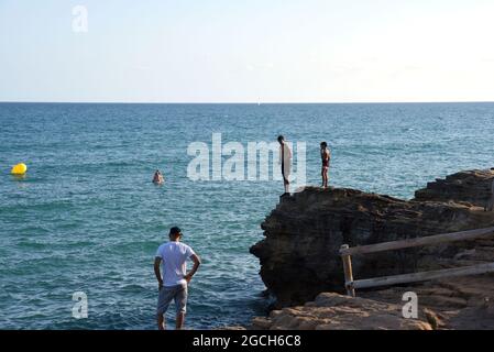 Roda de Bara, Espagne. 05 août 2021. Deux jeunes observent la région depuis une falaise avant de plonger dans la mer. Les jeunes sautent des falaises de la plage du Roc de Sant Gaieta à Roda de Bara (Tarragone Espagne), une pratique qui est interdite, dangereux et peut causer de graves blessures corporelles et même la mort par l'impact contre les roches. Crédit : SOPA Images Limited/Alamy Live News Banque D'Images